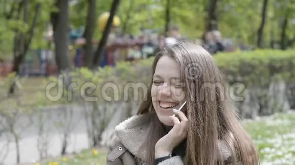 城市公园的女人微笑着用手机说话视频的预览图