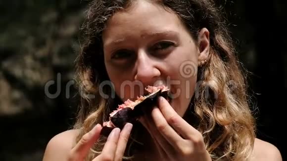 一个女人吃着多汁的成熟无花果享受大自然的味道慢动作的肖像视频的预览图
