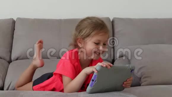 有平板电脑的漂亮少女躺在公寓的沙发上胶片静态摄像机视频的预览图