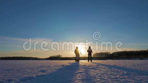 日落时幸福的家庭父亲母亲和小儿子在大自然中玩着雪冬散步视频的预览图