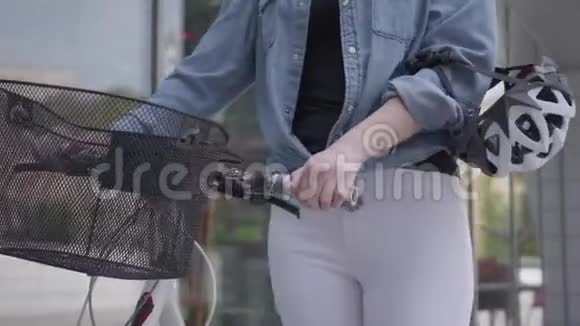 年轻的苗条迷人的金发女人穿着白色牛仔裤带着她的自行车靠近城市的商店窗户性感的女人视频的预览图