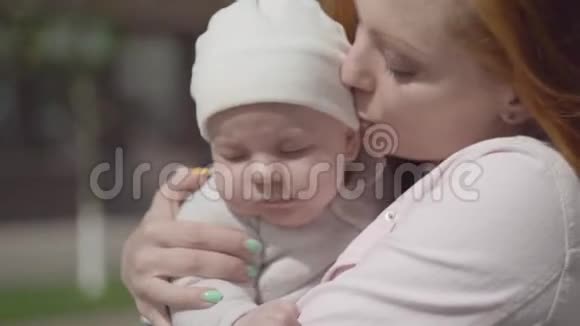 一幅美丽的红发女人抱着婴儿在院子里特写的肖像那位女士享受着视频的预览图