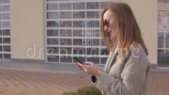 成年奢侈女性通过智能手机在城市街头发送短信春天视频的预览图