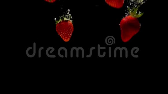 红色草莓溅落在透明的水中黑色背景视频的预览图