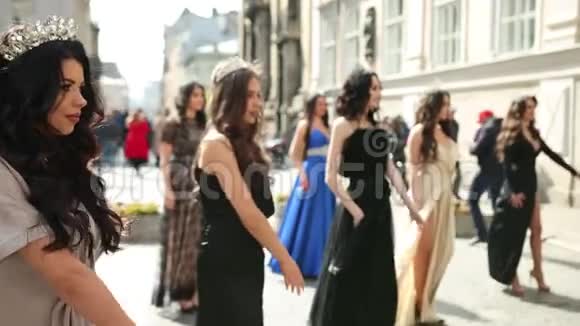 许多穿着连衣裙戴着皇冠的漂亮女孩在街上跳舞视频的预览图