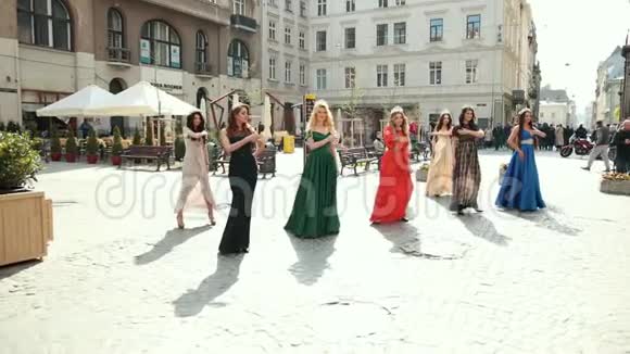 许多穿着连衣裙戴着皇冠的漂亮女孩在街上跳舞视频的预览图