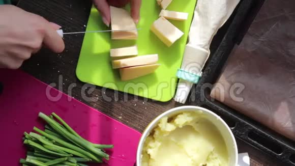 女人在切割板上切奶酪旁边的其他食材做菜饭土豆泥新鲜洋葱羽毛视频的预览图