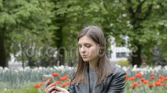 有魅力的女孩在公园里写短信视频的预览图