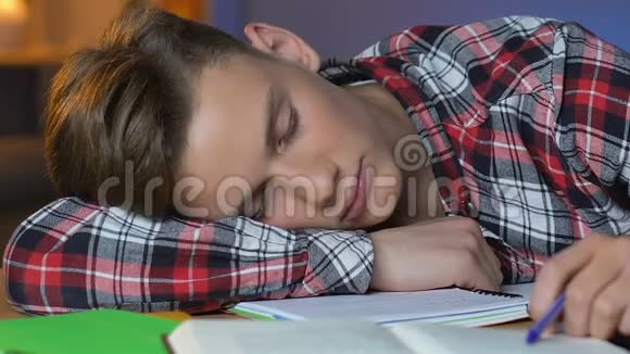 疲惫的男生睡在桌子上准备考试过度劳累的学生视频的预览图