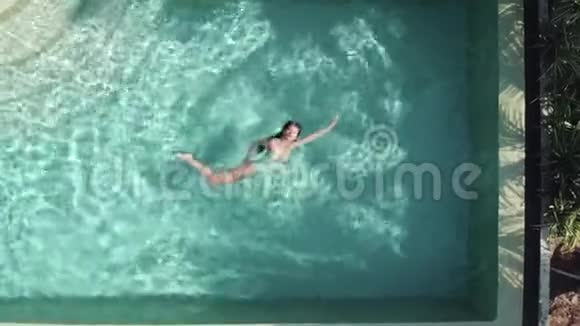 一位身穿比基尼在豪华别墅泳池里的年轻迷人女子视频的预览图