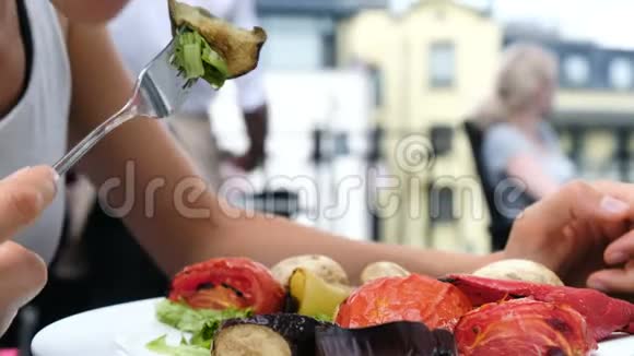 在夏季户外女人吃一个带有新鲜沙拉特写的烤菜叉视频的预览图