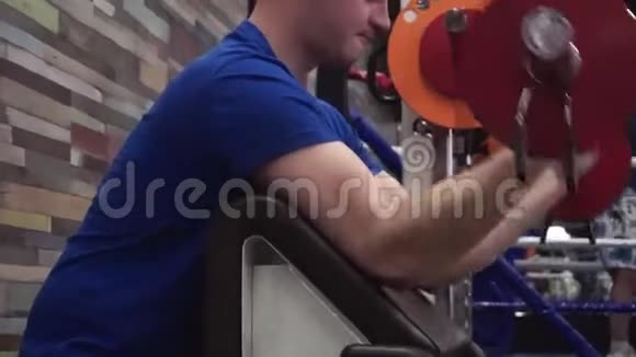漂亮的年轻人在健身房的机器上做二头肌卷发努力工作视频的预览图