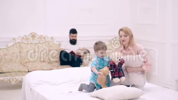年轻的家庭在家里玩一家人在家里的床上玩枕头大战父母可以自由支配时间视频的预览图