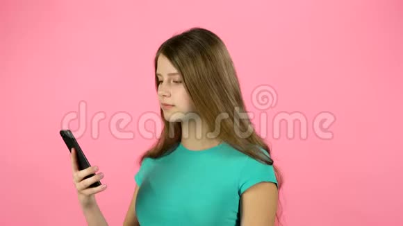 女孩在画室用手机对着粉红色背景说话视频的预览图