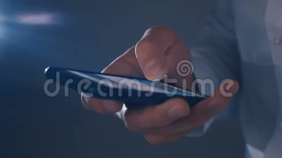 忙碌的商人在黑暗中用手指在智能手机上滚动视频的预览图