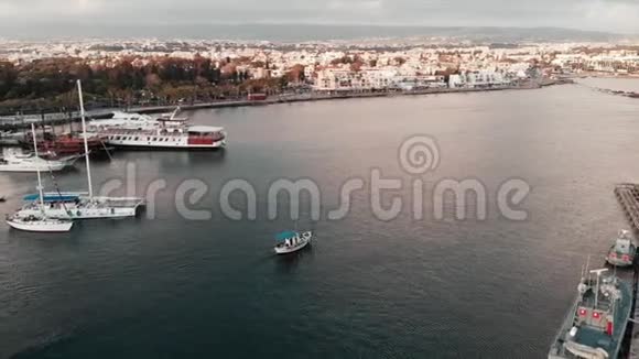 空中无人驾驶飞机从海上城市港口驶出的白色小渔船日落视频的预览图