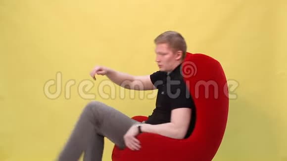 这个年轻人在黄色背景的扶手椅上跳舞很有趣视频的预览图