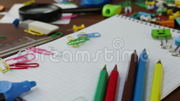 棕色木桌上的彩色铅笔回形针和笔记本视频的预览图