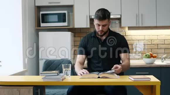 男人在家里坐在厨房里看书喝水视频的预览图