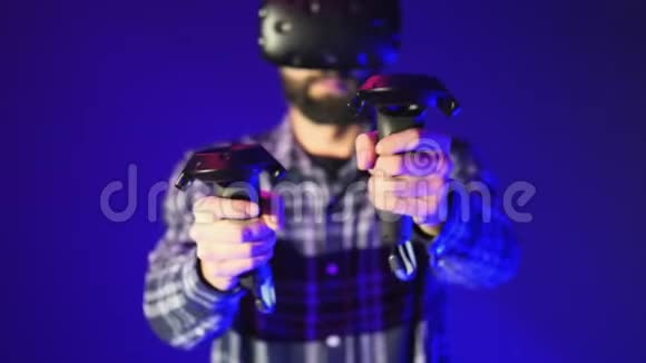 虚拟现实控制器的特写拍摄在一个射击虚拟现实游戏穿着蓝色背景VR耳机的男人视频的预览图