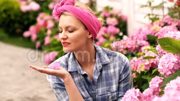 女人关心鲜花漂亮的女人手捧一朵绣球花坐在绣球花丛附近视频的预览图
