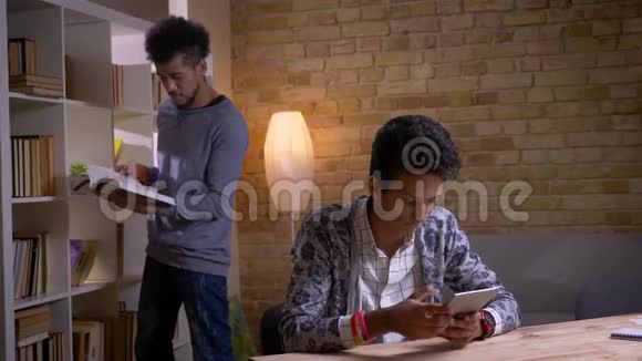 两名文化多样性的学生在学校图书馆室内学习的特写镜头印度男性在线学习视频的预览图
