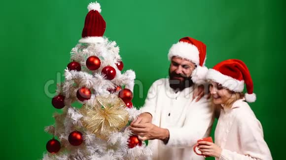 年轻夫妇在绿色的背景上装饰圣诞树新年庆祝理念可爱的一对视频的预览图