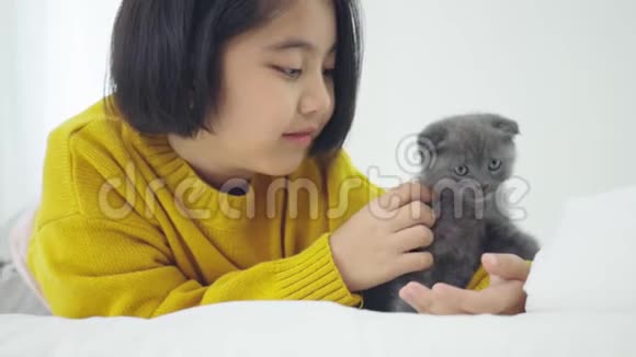 可爱的亚洲女孩和可爱的小猫玩耍漂亮的女孩紧紧地抱着一只猫在室内视频的预览图