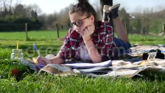少女在花园里做作业躺在草地上视频的预览图