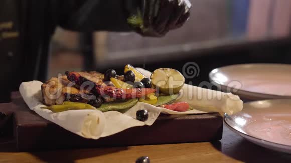 一个厨师的特写镜头他手里拿着黑色橡胶厨师手套把新鲜的迷迭香和柠檬叶放在盘子里视频的预览图