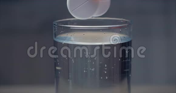 两片阿司匹林片落入一杯晶莹剔透的水中气泡在一杯水中沸腾健康观念视频的预览图