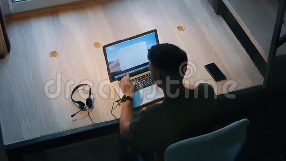 男人坐在桌子旁的笔记本电脑上工作总部概念后景视频的预览图