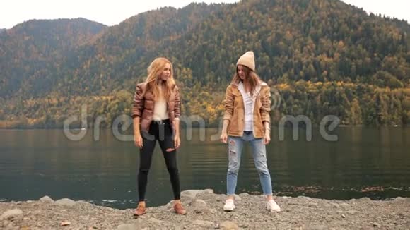 失败的两个女孩在湖上的背景下山舞为一个博客和笑声社交媒体旅游视频的预览图