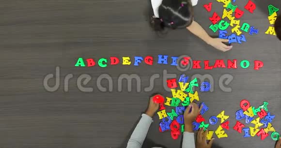 亚洲教师与亚洲学生一起玩彩色字母玩具的平躺场景视频视频的预览图