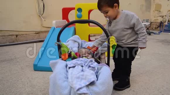 户外的小兄弟两岁的小男孩玩着皮钉做衣服带着小床送给弟弟视频的预览图