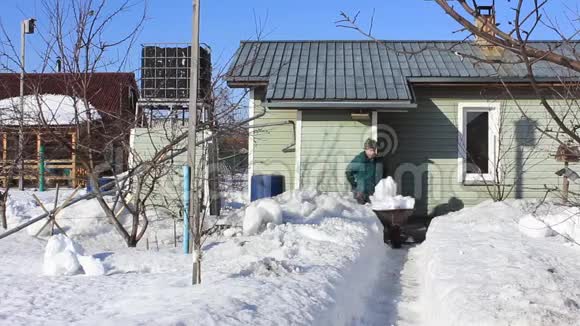 在一个大雪纷飞的冬天结束时老人从家里清除积雪视频的预览图