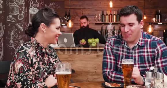 在乡村酒吧或餐厅喝啤酒和吃比萨饼的白种人夫妇放大镜头视频的预览图