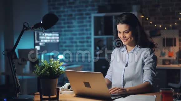 快乐的女商人深夜在办公室用电脑微笑视频的预览图