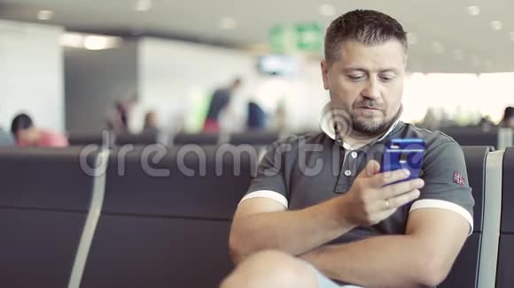 有胡子的成年人正在机场的手机上输入一条信息视频的预览图