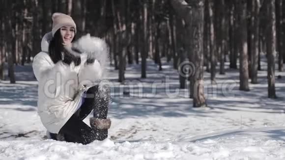 松树公园里一个美丽的女孩喜欢冬天下雪的天气她顽皮地把一把雪抱在头上视频的预览图