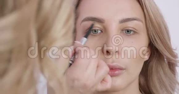 一个漂亮的金发女孩由一位女艺术家进行专业化妆视频的预览图