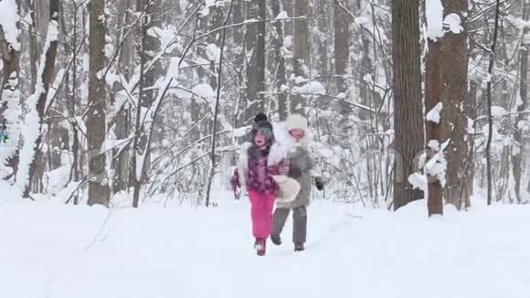 两个小女孩在冬天的森林里跑着玩雪球视频的预览图