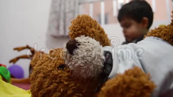 泰迪熊独自一人而老男孩在后台玩其他玩具视频的预览图