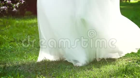 穿着婚纱的低镜头新娘在绿草上慢镜头转视频的预览图