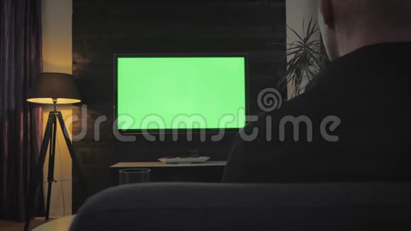 绿屏男在客厅看电视在肩膀上射击视频的预览图