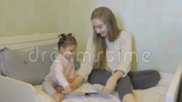 快乐的母亲和女儿一起在床上看书视频的预览图