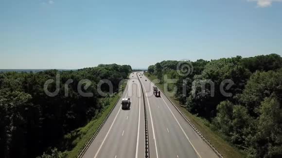 一条穿过乡村和绿色森林的公路的空中射击视频的预览图
