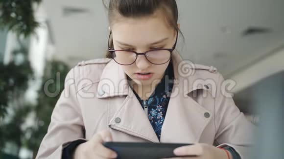 少女坐在咖啡馆里玩智能手机视频的预览图