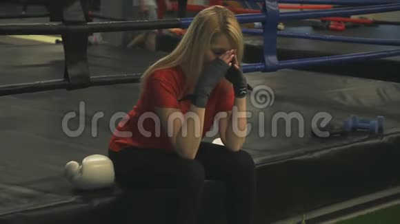 在训练结束后坐在拳击台上的女拳击手视频的预览图