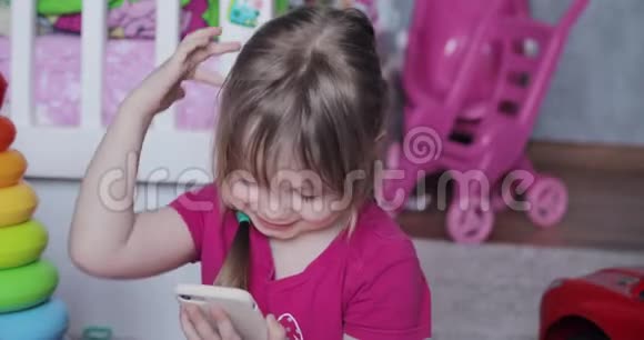 可爱的女孩在电话里玩游戏在家里微笑视频的预览图